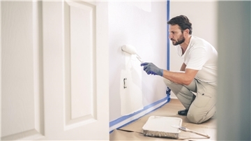 Ein Maler und Lackierer streicht eine Wand weiß.