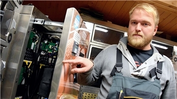 Mann zeigt auf beschädigte Automatentür