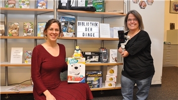 Marilies Mittelmaier (links) und Ina Küpper präsentieren die Bibliothek der Dinge. In der Stadtbücherei kann man ab sofort auch einiges an digitalen Artikeln ausleihen: vom Vorlesebären bis zum kleinen Roboter.