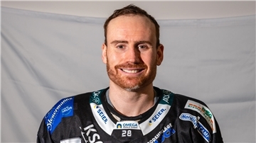 Eishockeyspieler im schwarzen Trikot vor weißer Wand
