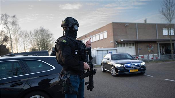 Maskierte und bewaffnete niederländische Polizisten bewachen einen Transport mit einigen der Verdächtigen, die vor dem Hochsicherheitsgebäude des Gerichts in Amsterdam eintreffen.