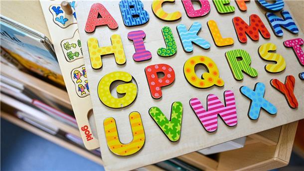 Buchstaben aus Holz in einem Kinderhaus. Material aus der Kindertagesbetreuung: Ein buntes Holzpuzzle steht symbolisch für ein Thema der Sitzung, in der auch eine Anfrage zur Kindertagespflege behandelt wird.