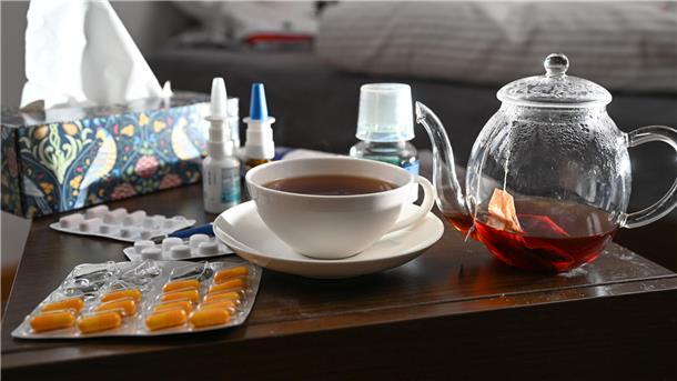 Was zur aktuellen Corona-Saison wichtig ist Medikamente und eine Kanne und Tasse Tee