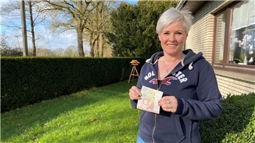 Eine Frau in blauer Strickhacke hält zwei Euroscheine in der Hand.