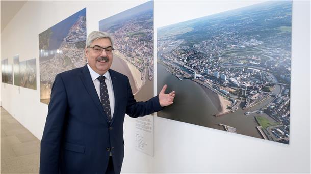 Melf Grantz bei der Ausstellungseröffnung vor einem Bild von Wolfhard Scheer.