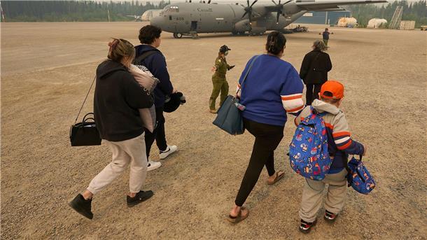 Mit dem Flugzeug vor den Flammen fliehen Menschen aus Kanada gehen zu einem Flugzeug. Das soll sie in Sicherheit bringen. Denn es toben schlimme Waldbrände.