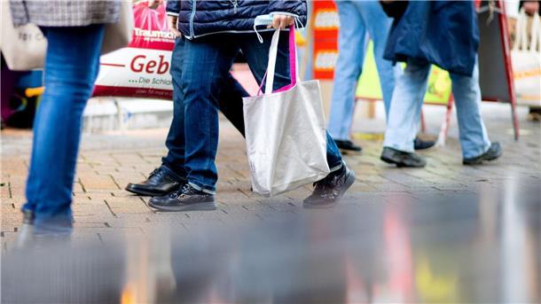 Menschen gehen mit Einkaufstaschen durch die Fußgängerzone der Innenstadt.