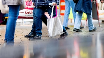 Menschen gehen mit Einkaufstaschen durch die Fußgängerzone der Innenstadt.