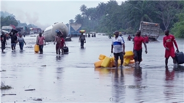 Menschen im nigerianischen Bayelsa waten durch überflutete Straßen.