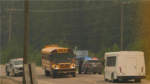 Mit dem Flugzeug vor den Flammen fliehen Menschen in Kanada werden wegen Waldbränden in Sicherheit gebracht. Ein Schulbus fährt sie zu einem Flughafen.