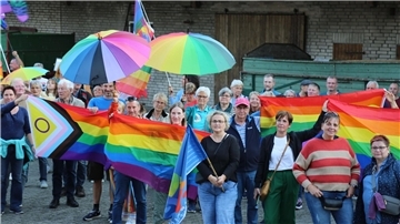 Menschen mit Regenbogenflaggen und -schirmen beteiligten sich an einer Kundgebung.
