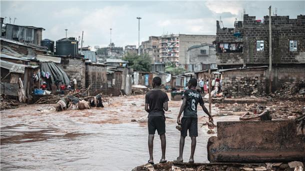 Fluten in Ostafrika treffen Slumbewohner und Urlauber Menschen stehen am Ufer eines überfluteten Flusses in den Mathare-Slums in Nairobi.