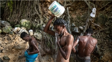 Menschen waschen sich in einer Schlucht in Port-Au-Prince.