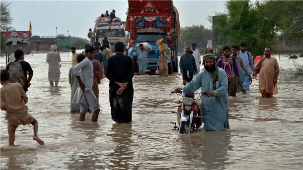 Weltklimarat fordert drastische Klimaschutzschritte vor 2030 Menschen waten im August 2022 im pakistanischen Nasirabad durch auf einer überschwemmten Straße durchs Hochwasser.