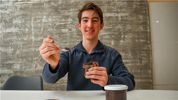Ein Junge hält eine Schokoladencreme in der Hand.