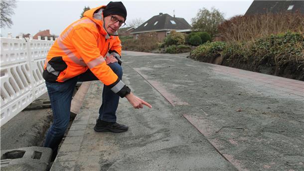 Michael Schöne (Niedersächsische Landesbehörde für Straßenbau und Verkehr) zeigt die Sinussteine, die vor Hauseinfahrten verlegt werden und den Höhenunterschied zwischen Radweg und Fahrbahn ausgleichen.