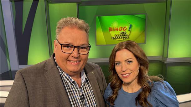 Ein Mann  und eine Frau stehen in einem Fernseh-Studio.