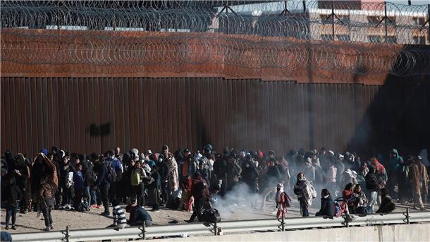 Migranten aus Lateinamerika stehen an der Grenzmauer zwischen Mexiko und den USA.