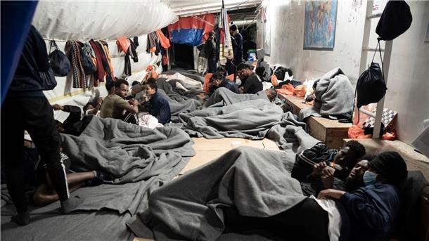 Lage auf Rettungsschiffen: Menschen springen ins Wasser Migranten sind in Decken eingewickelt, während sie sich auf dem Deck des Rettungsschiffs Ocean Viking im Mittelmeer nahe der Küste Siziliens in Süditalien versammeln.