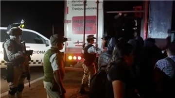 Migranten verlassen im Beisein von Sicherheitskräften den Lastwagen - die meisten von ihnen stammen aus Guatemala.