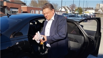 Mann mit Kuscheltier in der Hand steht am Auto