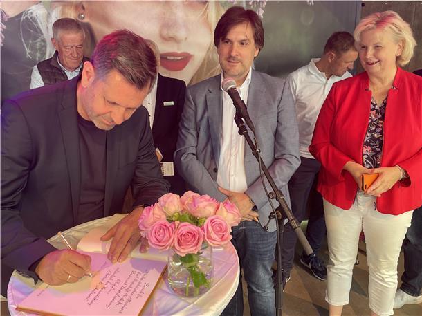 Minister Olaf Lies trägt sich ins goldene Buch der Stadt Nordenham ein, wozu ihn Bürgermeister Nils Siemen eingeladen hat. Rechts schaut die Berner Landtagsabgeordnete Karin Logemann zu.