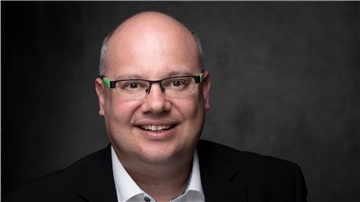 Mann mit Brille, weißem Hemd und schwarzem Sakko