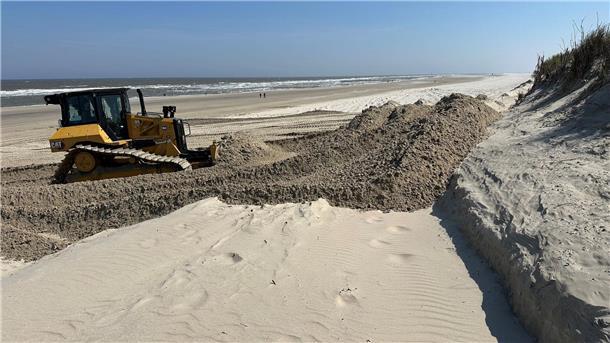 Mit einem Baustellenfahrzeug wird ein Strand wieder mit Sand aufgefüllt. Wie man Küsten besser schützen kann, darüber machen sich Fachleute viele Gedanken.