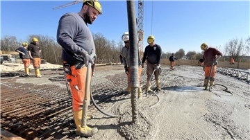 Mit einer Betonpumpe wird der Beton in die Holzverschalung für den Stahlbeton gegossen. Dabei sorgen die Bauarbeiter mit den Rüttelflaschen in den schmalen Schläuchen dafür, dass sich das Material durch Vibrationen in allen Fugen verteilt. 