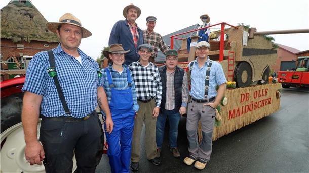 Driftsether Team triumphiert beim Erntefest mit Oldtimer-Mähdrescher Eine Gruppe Menschen steht vor einem Trecker mit Anhänger