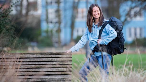 Warum Maria Luisa Kuzmic ihre neue Heimat am liebsten zu Fuß entdeckt Eine Frau mit braunen Haaren und einer blauen Jacke steht mit einem Wanderrucksack im Grünen: Wanderliebhaberin Maria Luisa Kuzmic aus Bremerhaven.