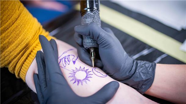 Diese junge Frau findet im Tattoo-Studio auf dem Dorf ihre Bestimmung Ein Muster wird auf einen Unterarm tätowiert.