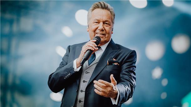 Roland Kaiser hält ein Mikrofon in der Hand uns singt.