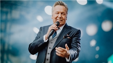 Roland Kaiser hält ein Mikrofon in der Hand uns singt.