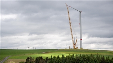 Während dichte, dunkle Wolken am Himmel ziehen, werden im Windpark Obergeckler riesige Windkraftanlagen errichtet.