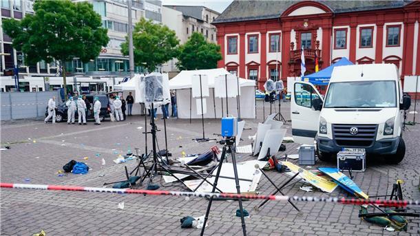 Angriff in Mannheim löst neue Debatte über Abschiebungen aus Mitarbeiter der Spurensicherung stehen auf dem Marktplatz hinter einem zertrümmerten Stand.