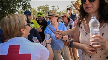 Mitarbeiter des Griechischen Roten Kreuzes verteilen vor der Akropolis Wasserflaschen an  Besucher.