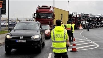 Zollbeamte vor Autokolonne.