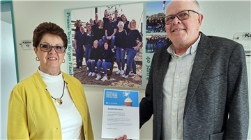 Eine Frau und ein Mann halten eine Urkunde in die Kamera.