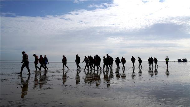 Mutmaßliche Migranten bei Dungeness, nachdem sie nach einem Zwischenfall mit einem kleinen Boot im Ärmelkanal mit einem Rettungsboot der Royal National Lifeboat Institution (RNLI) an Land gebracht wurden.