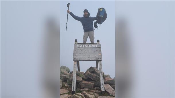 Ein Mann steht am Zielpunkt des AT, dem Mount Katahdin.