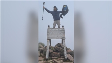 Ein Mann steht am Zielpunkt des AT, dem Mount Katahdin.