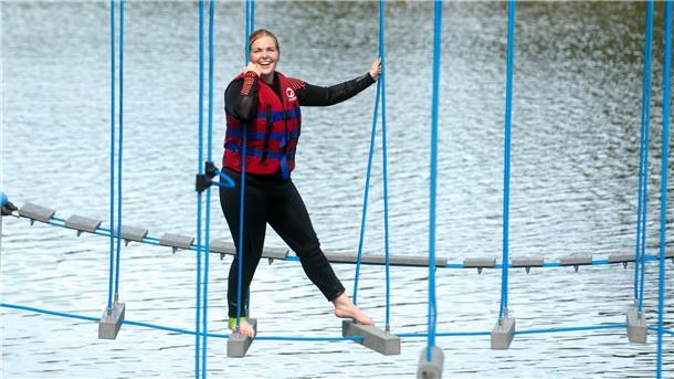 Eine Frau balanciert auf einem Kletterparkour