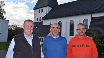 Drei Männer vor einer Kirche