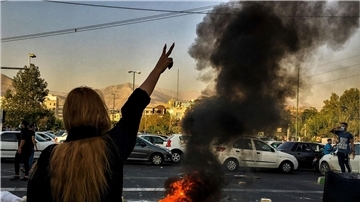 Nach dem Tod der 22-jährigen Mahsa Amini steht eine Frau während einer Demonstration in Teheran vor einem brennenden Autoreifen.