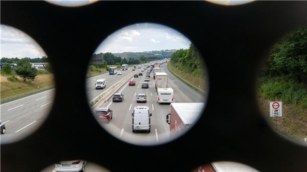  Zahlreiche Autos stehen auf der Autobahn im Stau, Aufnahme durch das Geländer einer Brücke