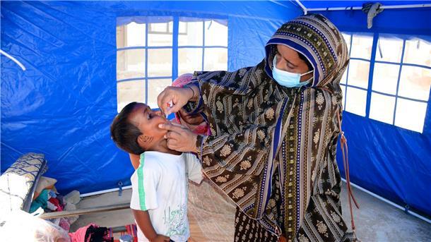 Gates-Stiftung: Polio könnte bis 2026 ausgerottet sein Nach den schweren Überschwemmungen in Pakistan verabreicht eine Mitarbeiterin des Gesundheitswesen einem Kind eine Schluckimpfung gegen Polio.