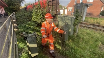 Mann in orangem Arbeitsanzug betätigt eine Kurbel an den Bahnschienen.