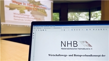 Laptop im Vordergrund, Präsentation im Hintergrund.