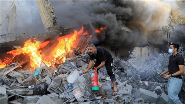 Bodenoffensive in Gaza erwartet - Nahost-Flächenbrand droht Nach einem israelischen Luftangriff in der Stadt Khan Yunes im südlichen Gazastreifen löschen Menschen das Feuer in den Trümmern.